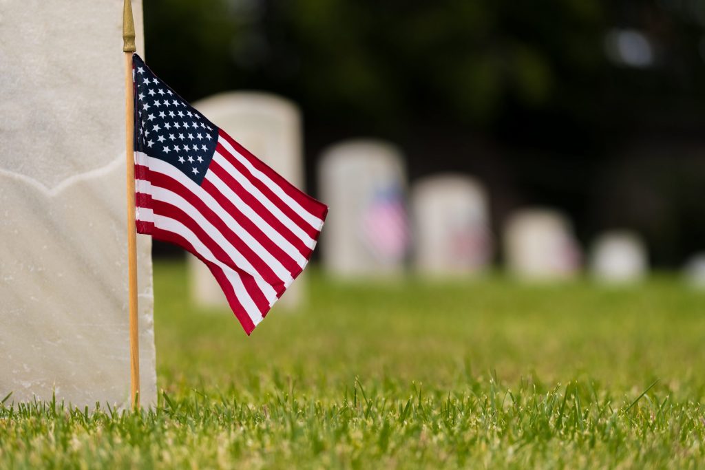American flag in front of gravestone American flag in front of gravestone