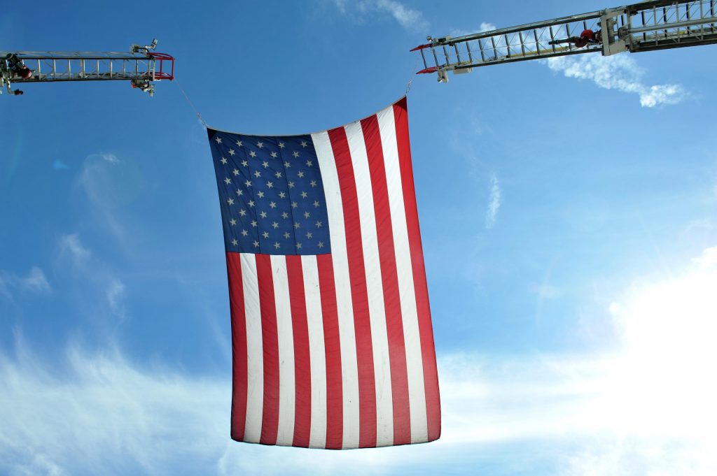 American flag held up by firetruck ladders