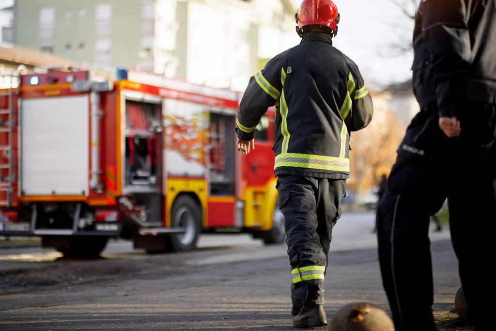 Fireman in uniform in front of fire truck going to rescue and protect.