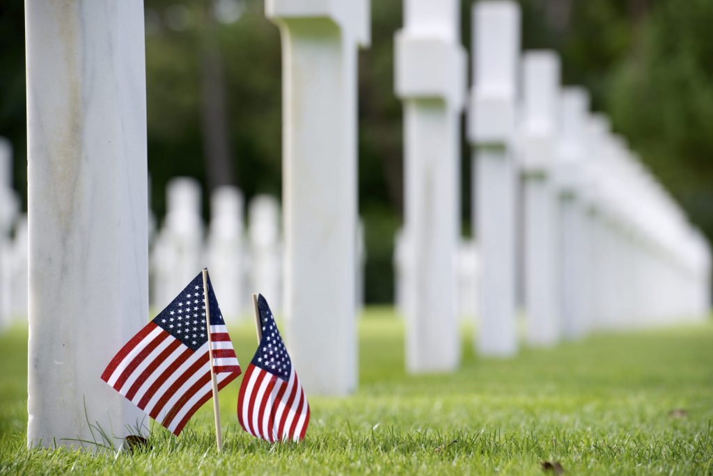 Two small American flags in front of white tombstone