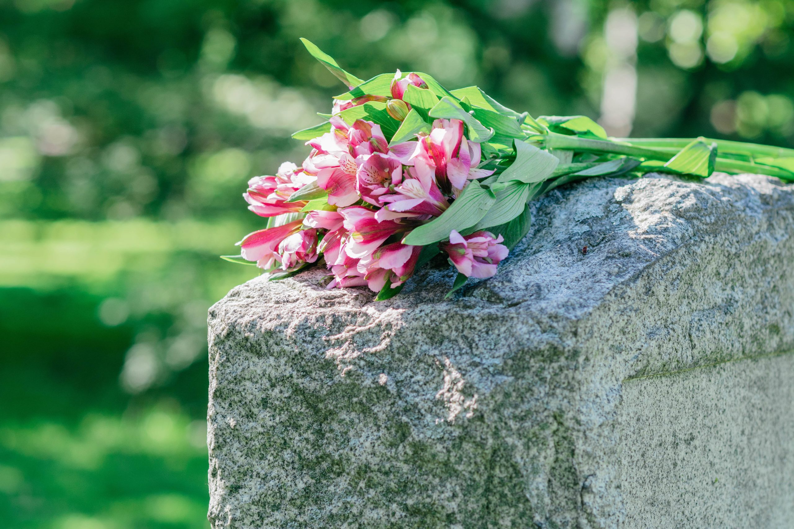 bouquet of pink flowers on top of tombstone