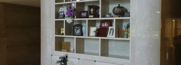 shelves in a mausoleum with flowers and ribbons from visitors